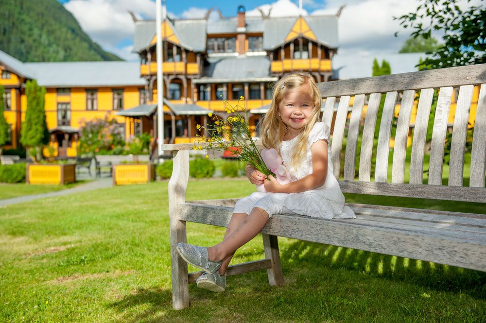 little girl sits on a bench in front of the Dalen Hotel