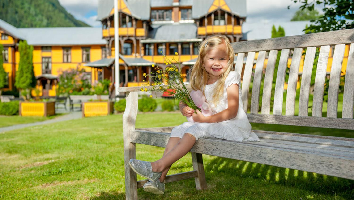 little girl sits on a bench in front of the Dalen Hotel