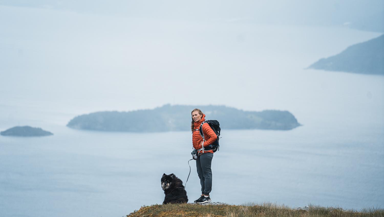 Woman and dog hiking in the mountains over the Hardangerfjord.