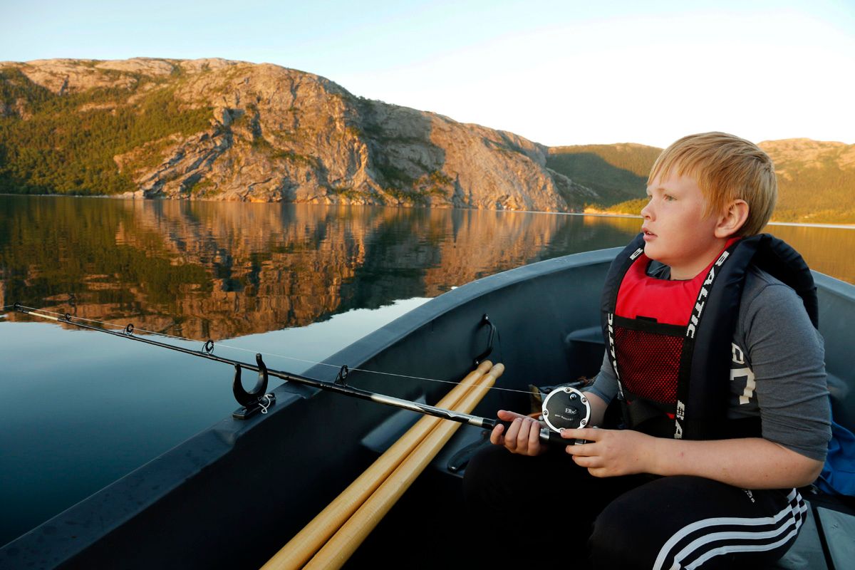 Gutt med fiskestang i båt ved havet, Flatanger Camping, Namdalen.