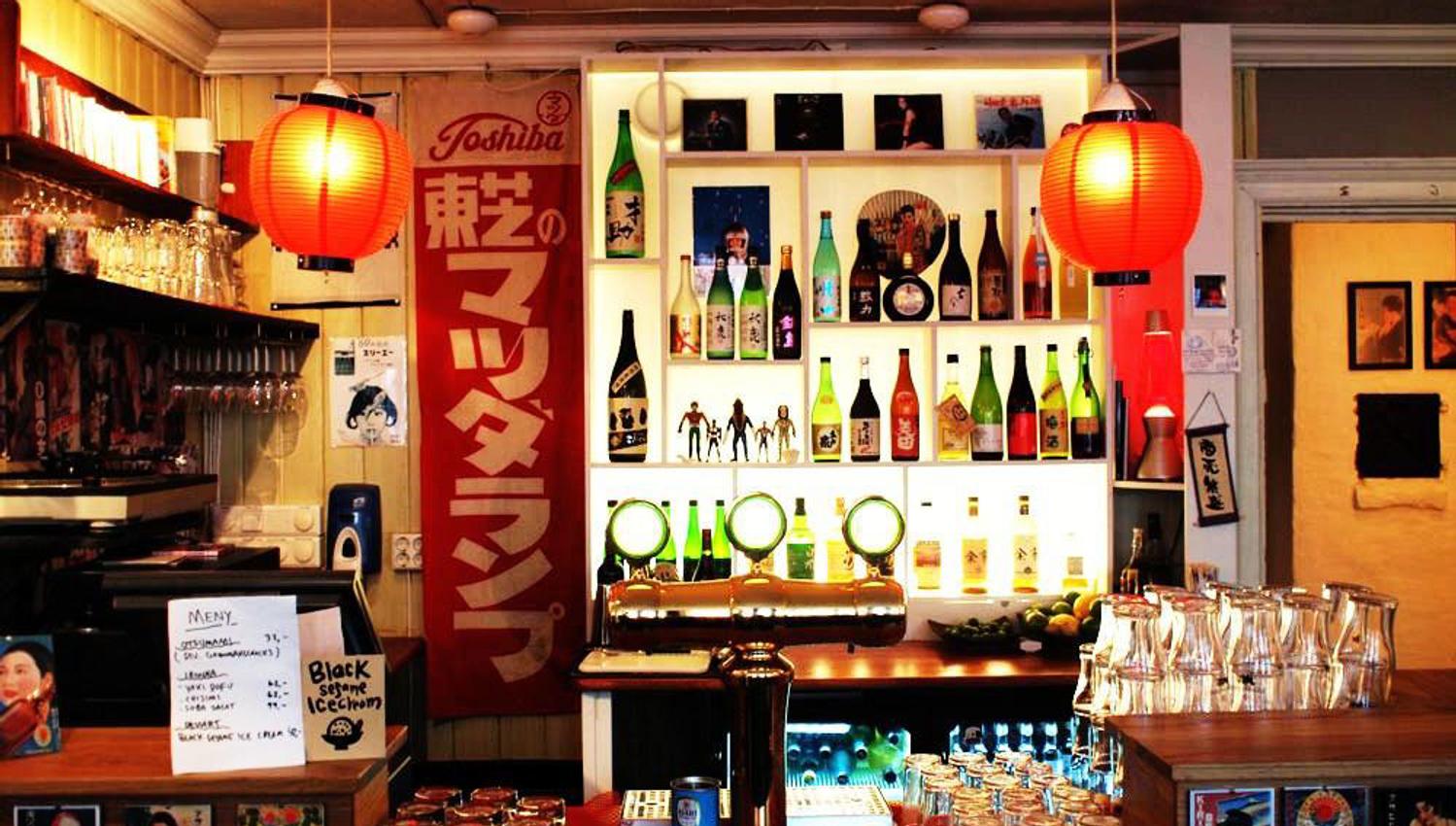 Bar area with rice lamps, various beverages and glasses.