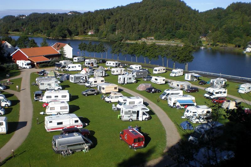 Wohnmobile/Wohnwagen stehen in Reihen, mit einem Weg zwischen den Reihen, und der Fluss Mandalselva liegt ganz in der Nähe.