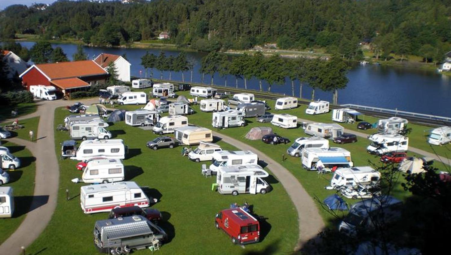 Wohnmobile/Wohnwagen stehen in Reihen, mit einem Weg zwischen den Reihen, und der Fluss Mandalselva liegt ganz in der Nähe.