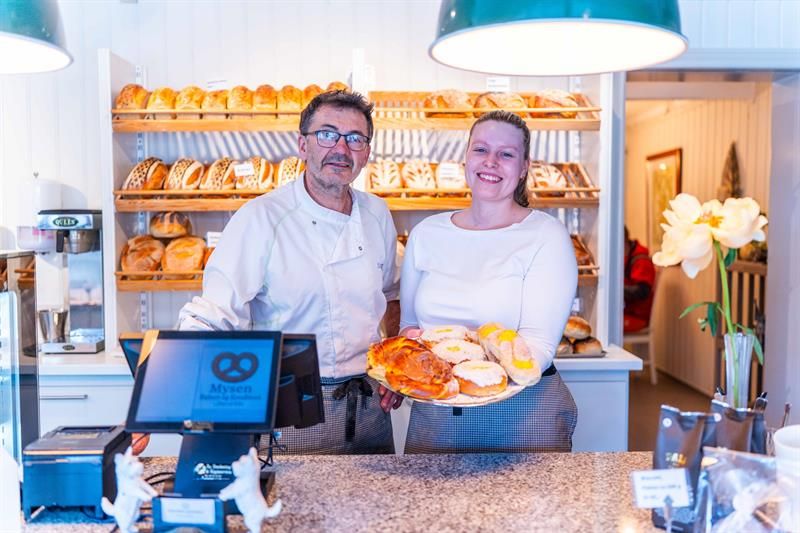 Ansatte bak disken i et bakeri som holder frem bakst