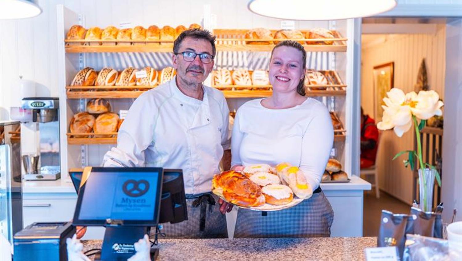 Ansatte bak disken i et bakeri som holder frem bakst