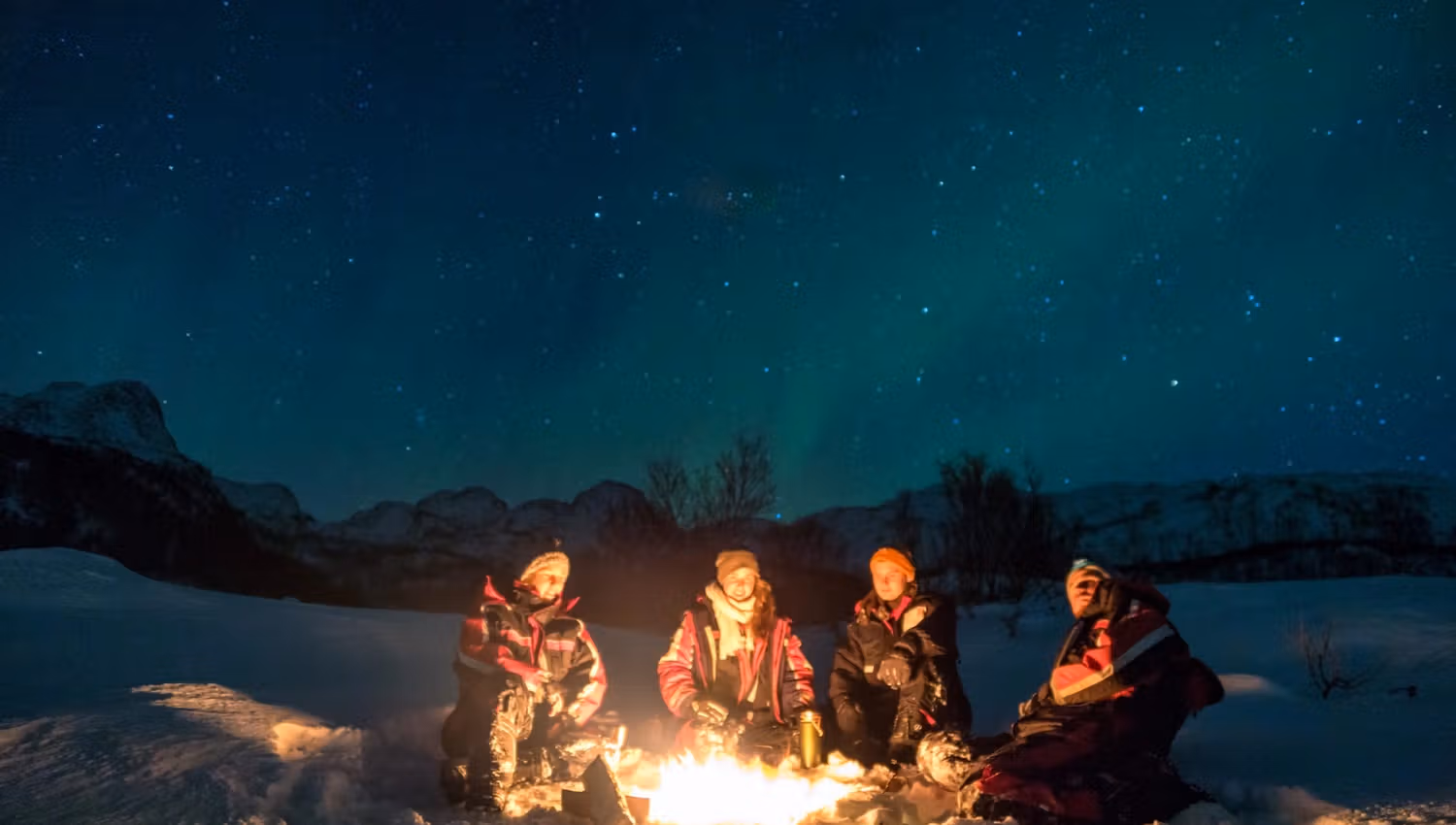 Experience the magic of winter nights as four friends gather around a crackling campfire, surrounded by snow and a breathtaking starry sky. The warmth of the fire contrasts beautifully with the cold, creating a perfect atmosphere for storytelling and laug