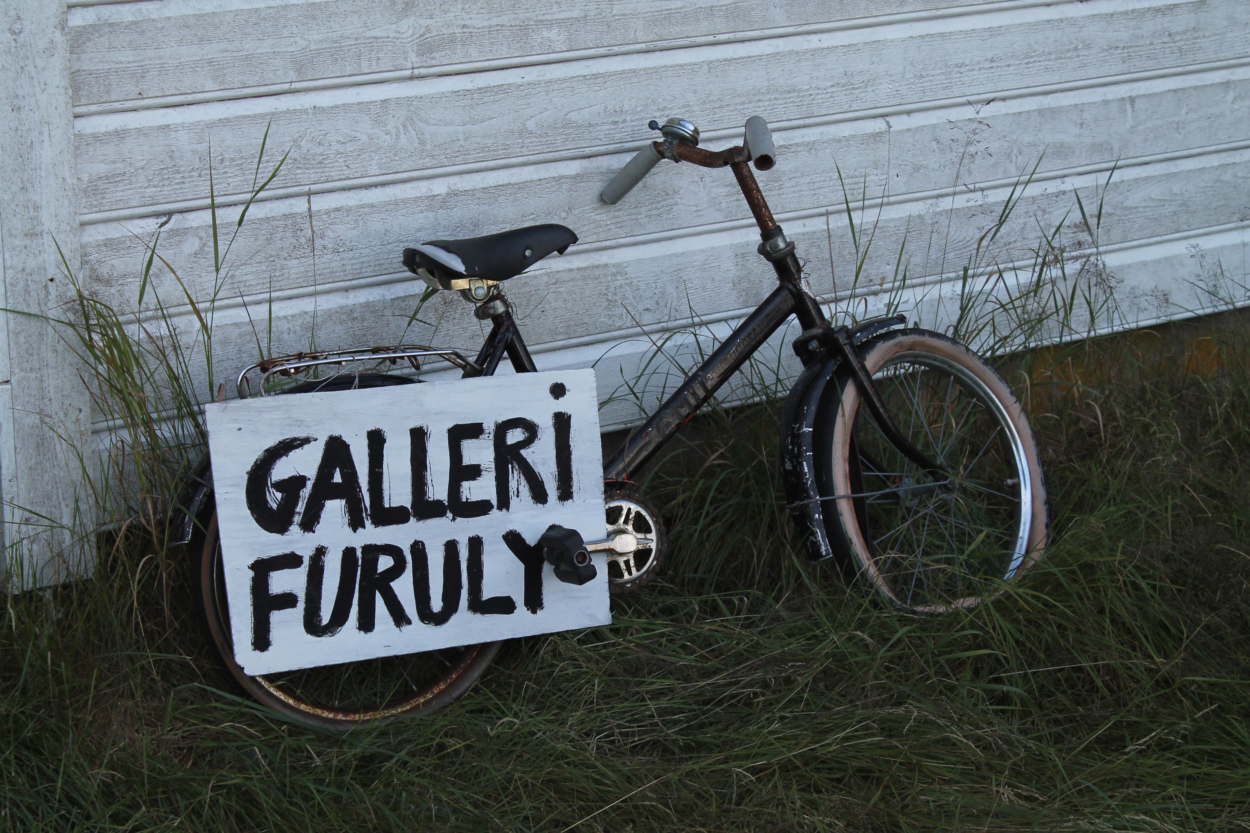 Detailaufnahme eines Fahrrads mit einem Schild mit der Aufschrift "galleri furuly"