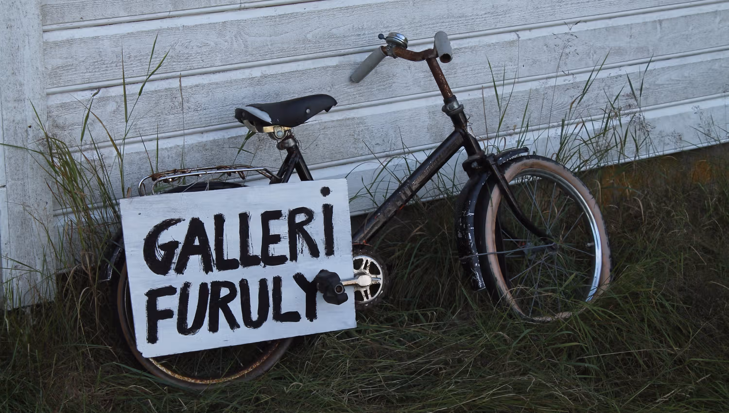 Detailaufnahme eines Fahrrads mit einem Schild mit der Aufschrift "galleri furuly"