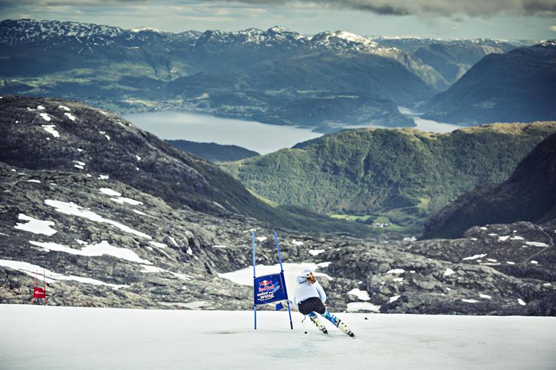 Alpinist køyrer ned sommarsnøen på Fonna Glacier Ski Resort med Hardangerfjorden i bakgrunnen.