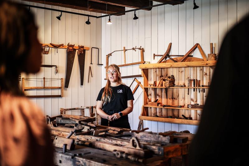 An employee demonstrating various tools used for wood carving and sculpture.