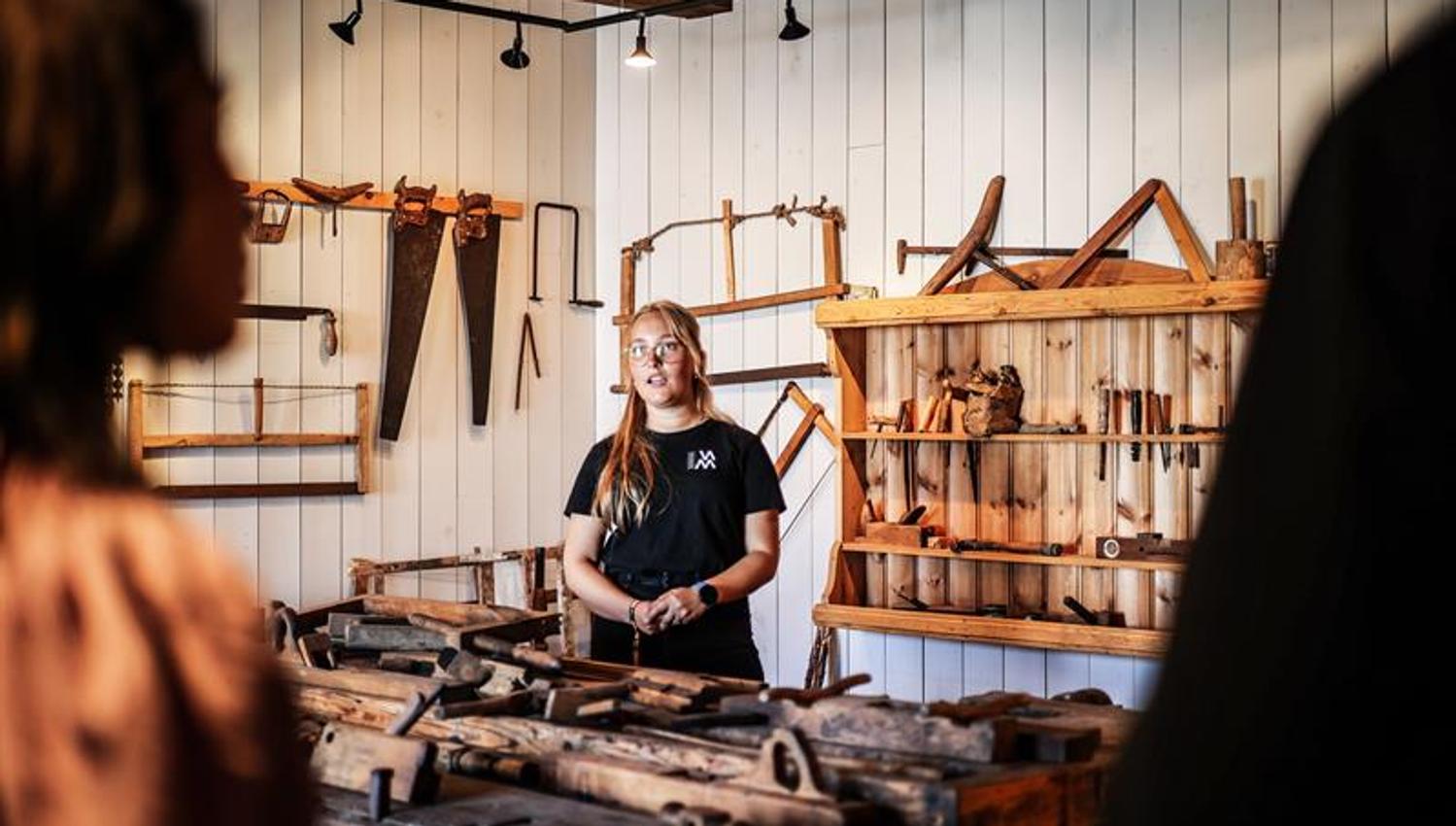 An employee demonstrating various tools used for wood carving and sculpture.