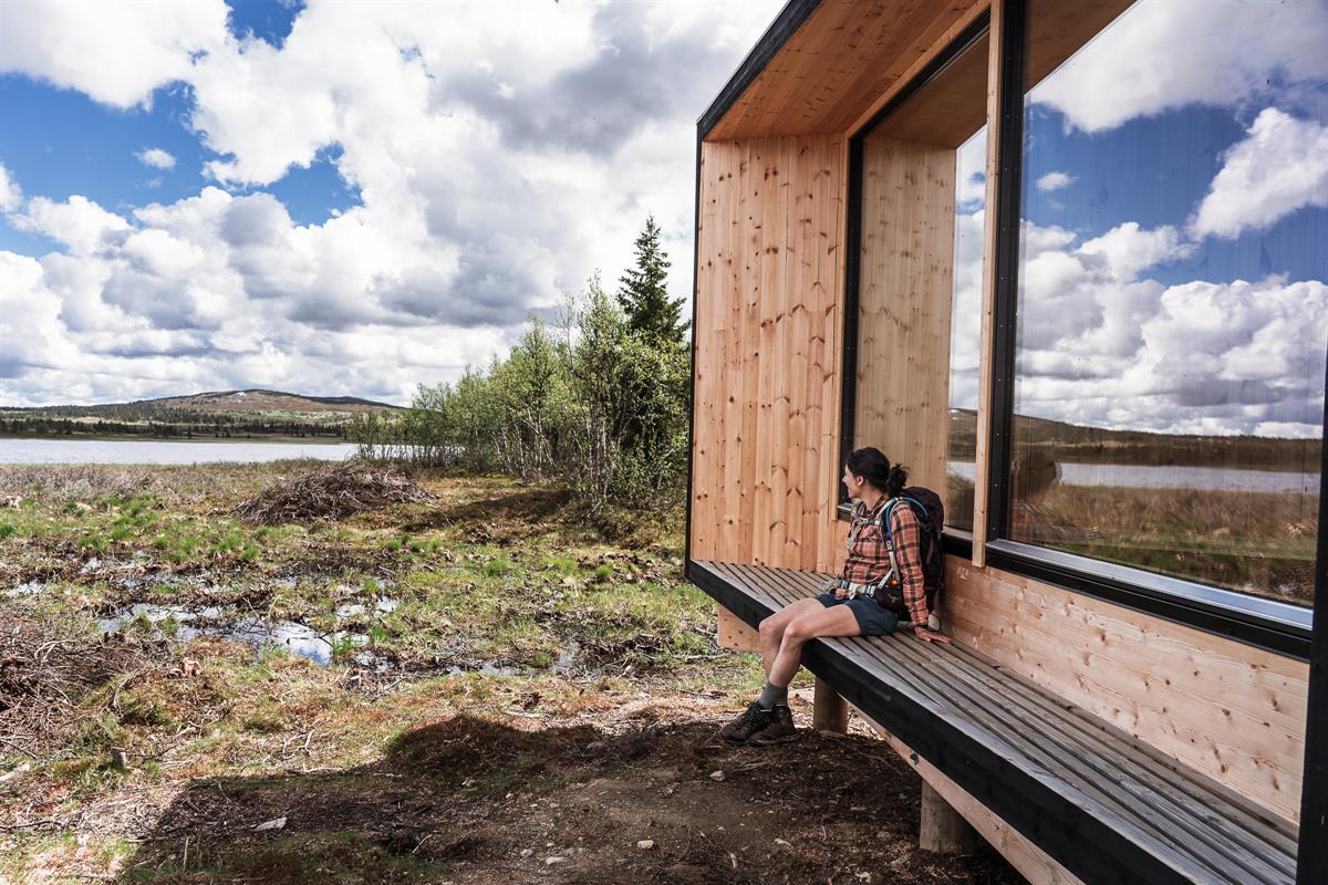  Person sitting by a modern cabin in the mountains