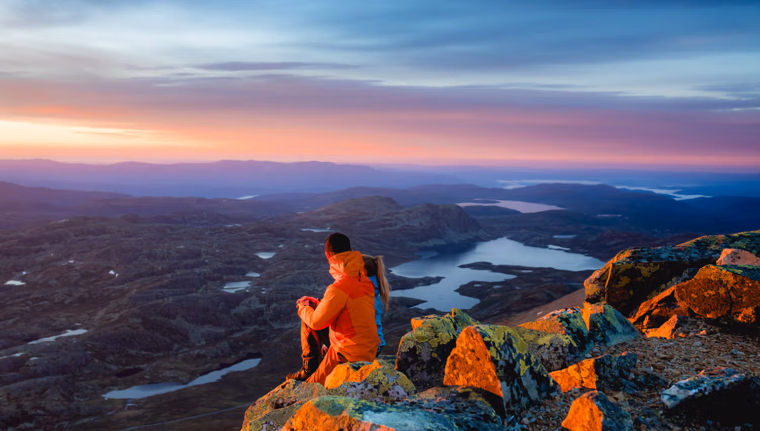 par sitter på toppen av Gaustatoppen i kveldsola