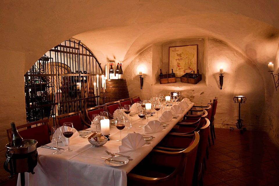 A long table with a white cloth set for dining, with wine glasses.