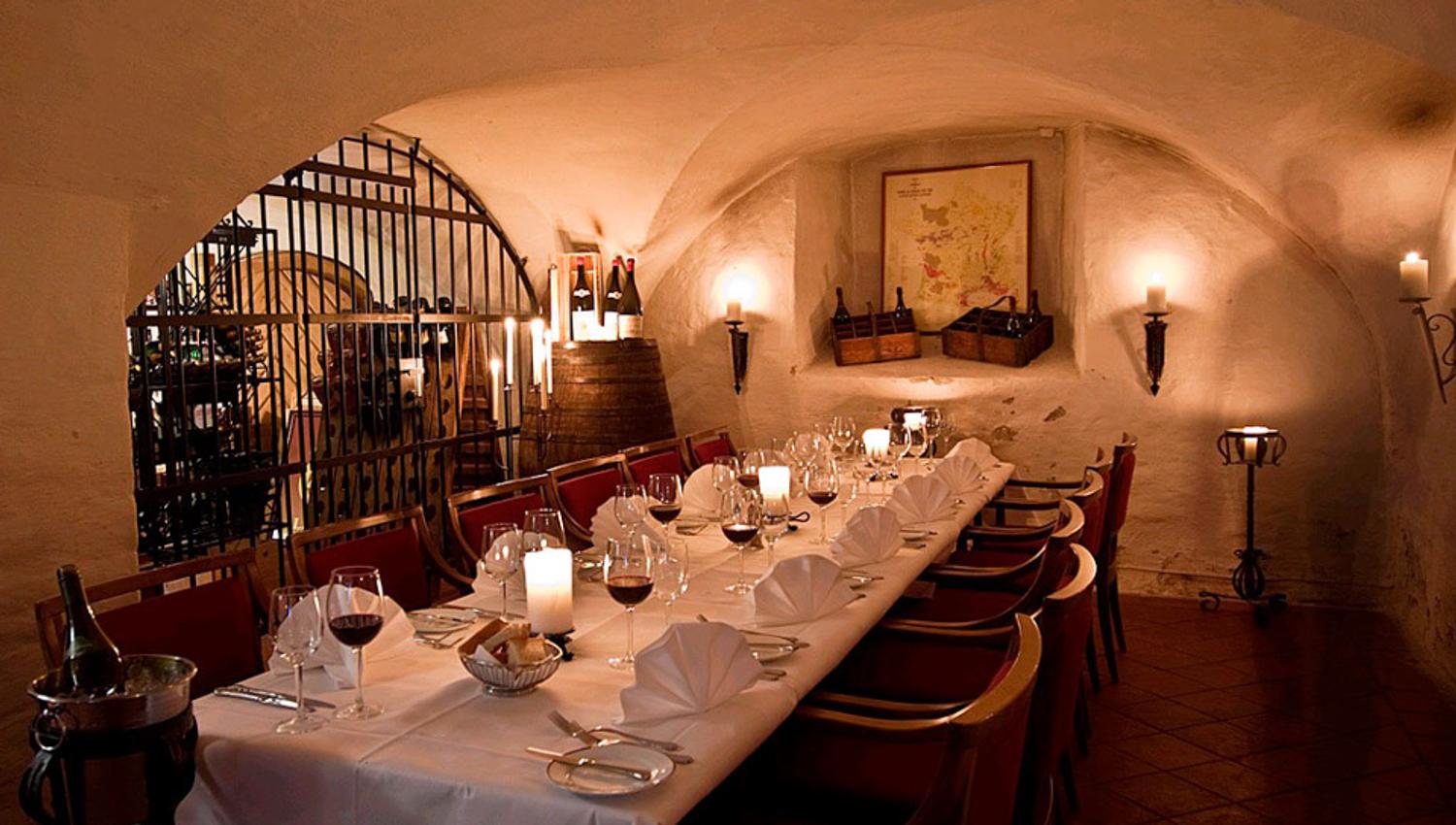 A long table with a white cloth set for dining, with wine glasses.