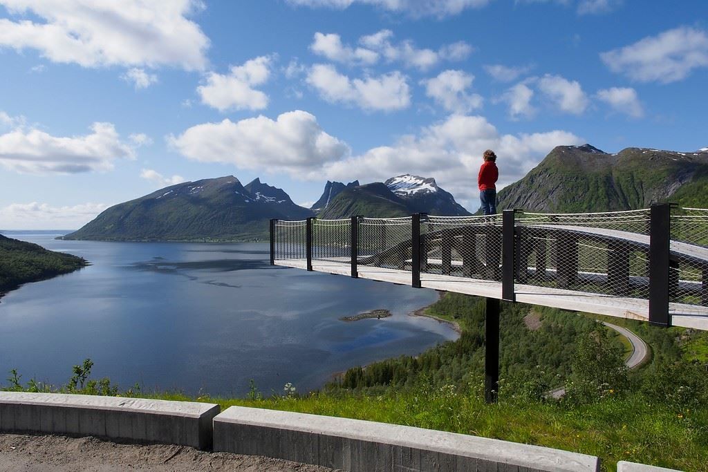 En besøkende på en utsiktsplattform med utsikt over fjord og fjell på Senja