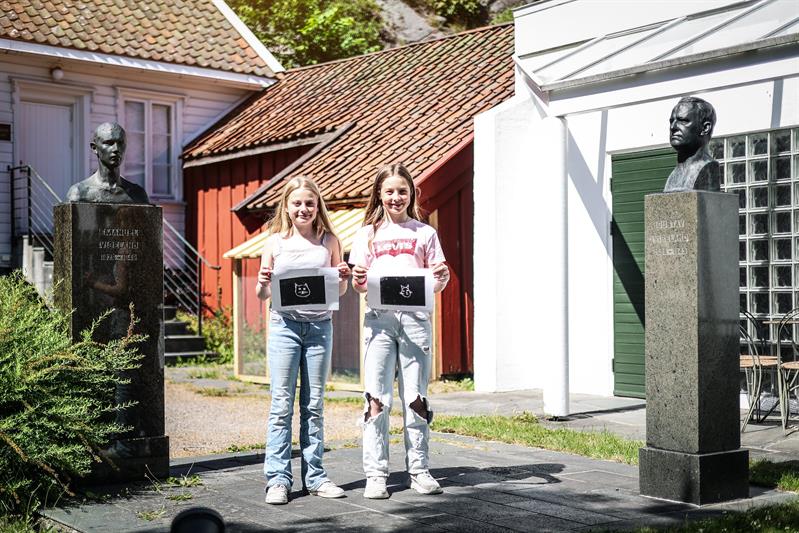 Two smiling girls show the woodcut they have made.