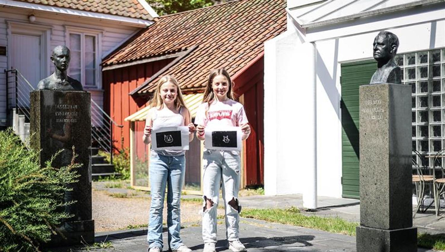 Two smiling girls show the woodcut they have made.