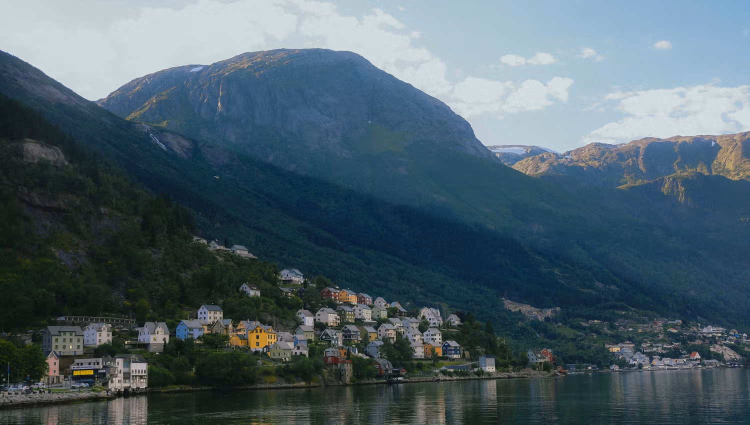 Evening light over Odda with colorful houses scattered along the steep hillsides.