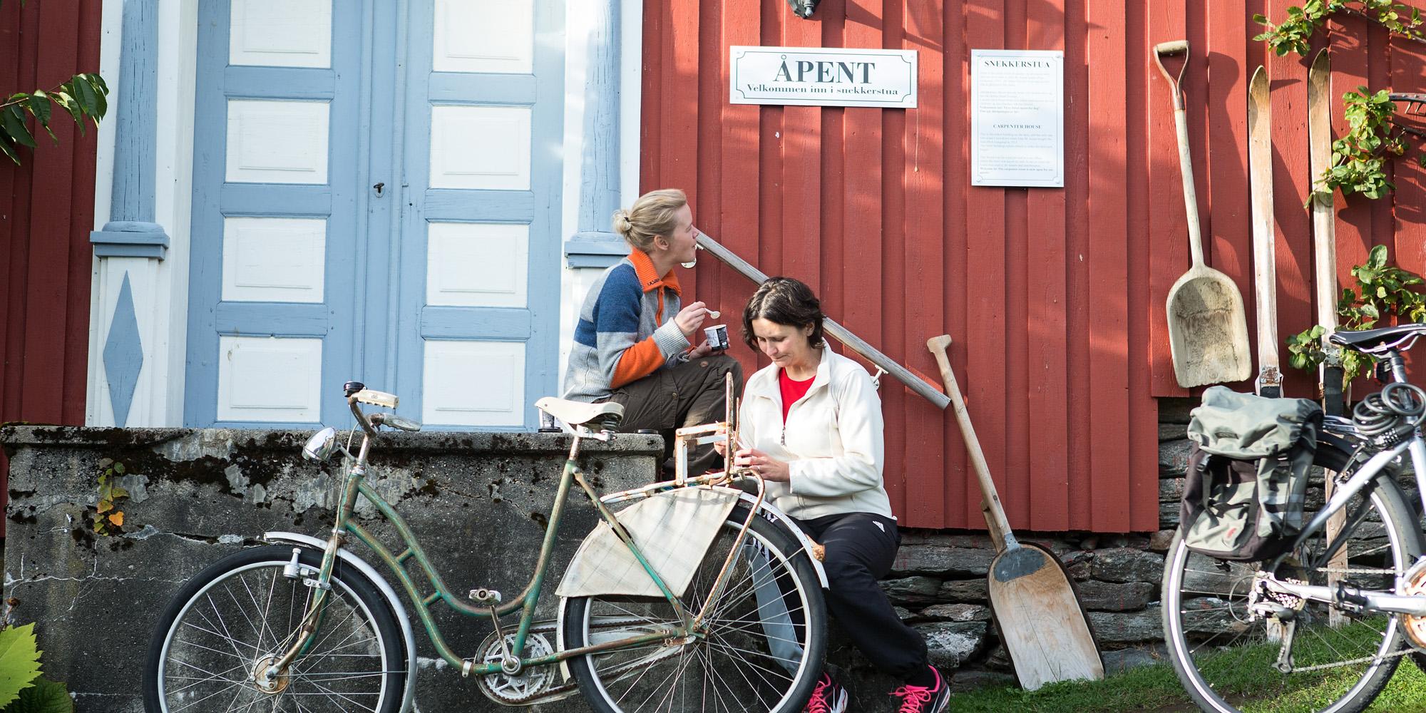 Syklister tar seg en pust i bakken hos Gangstad med is i gårdstunet.