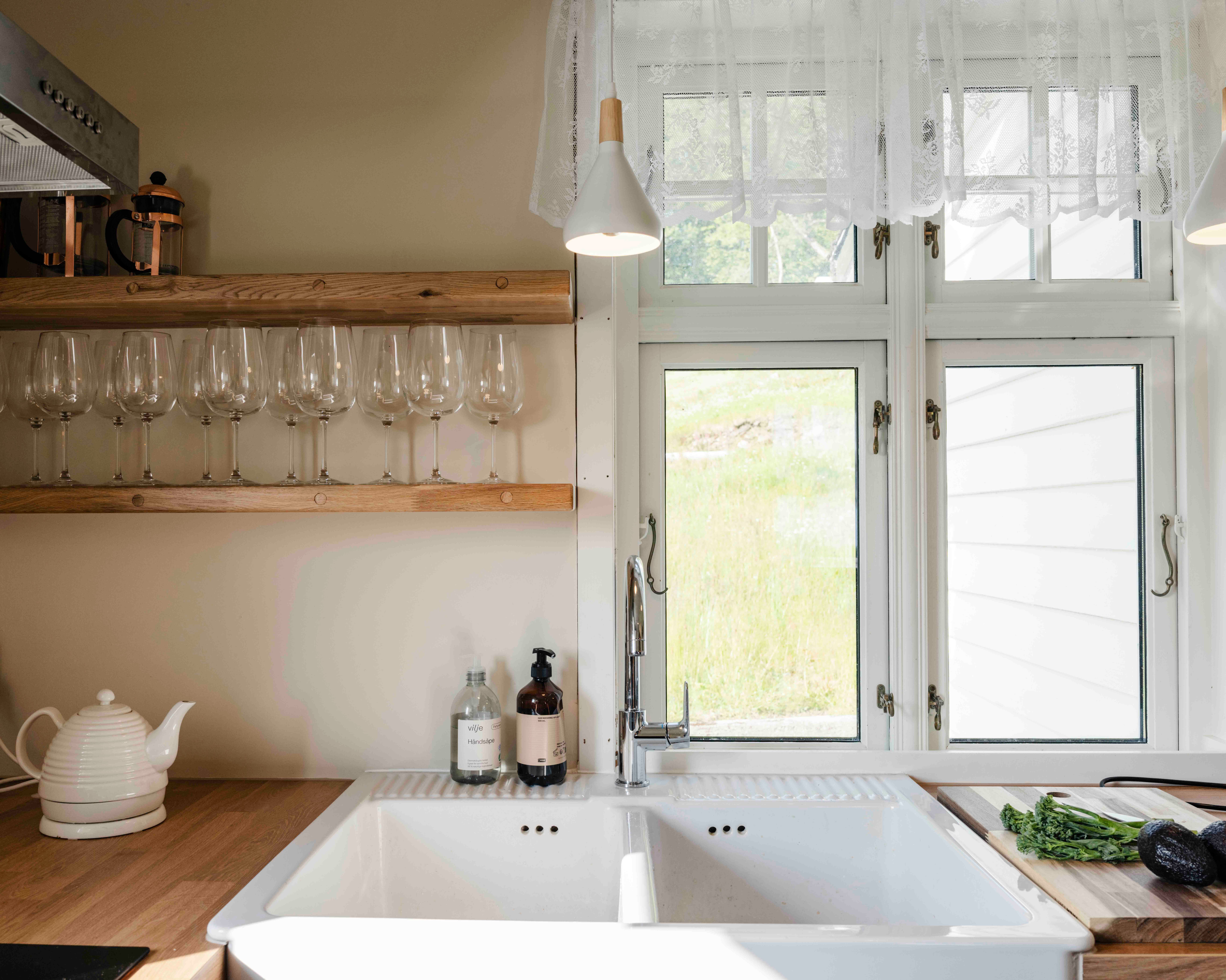 Bright and modern kitchen with wine glasses and a peaceful view at Stigen Fjordlodge in Hardanger.