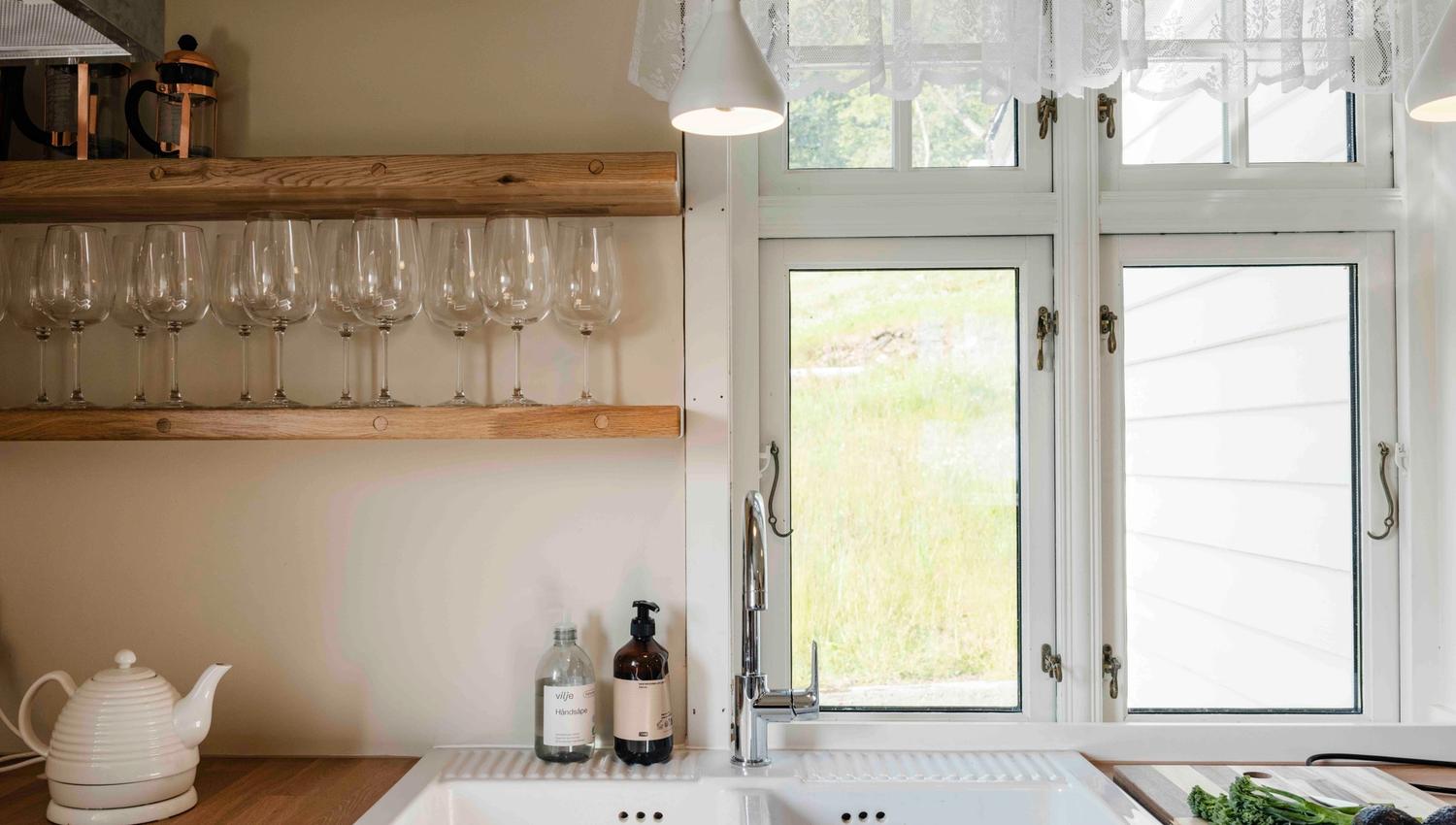 Bright and modern kitchen with wine glasses and a peaceful view at Stigen Fjordlodge in Hardanger.