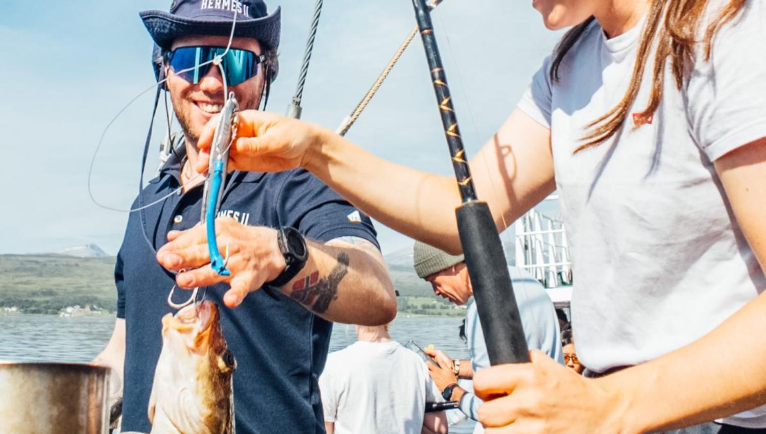 Guide hjelper gjest med fanget fisk