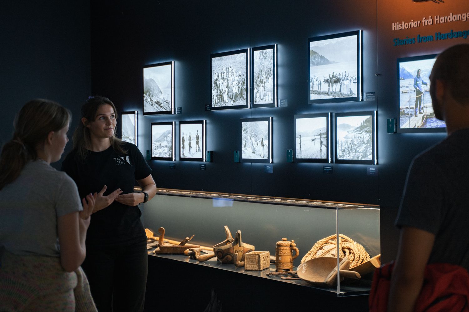 Exhibition wall with historical photos and traditional Hardanger artefacts in the “This is where we live” display.