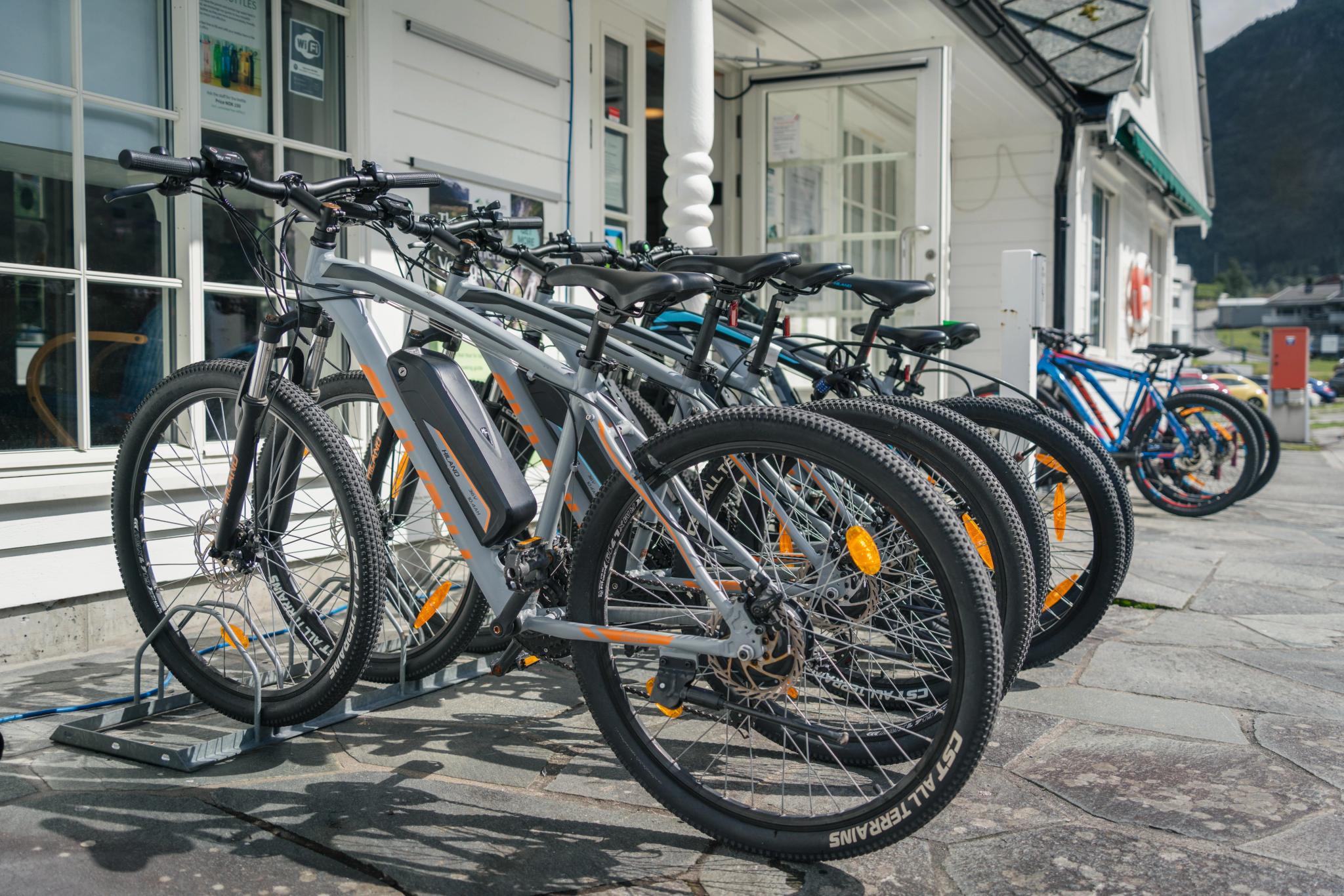 A few e-bikes and regular bikes on a bike rack outside the tourist office.