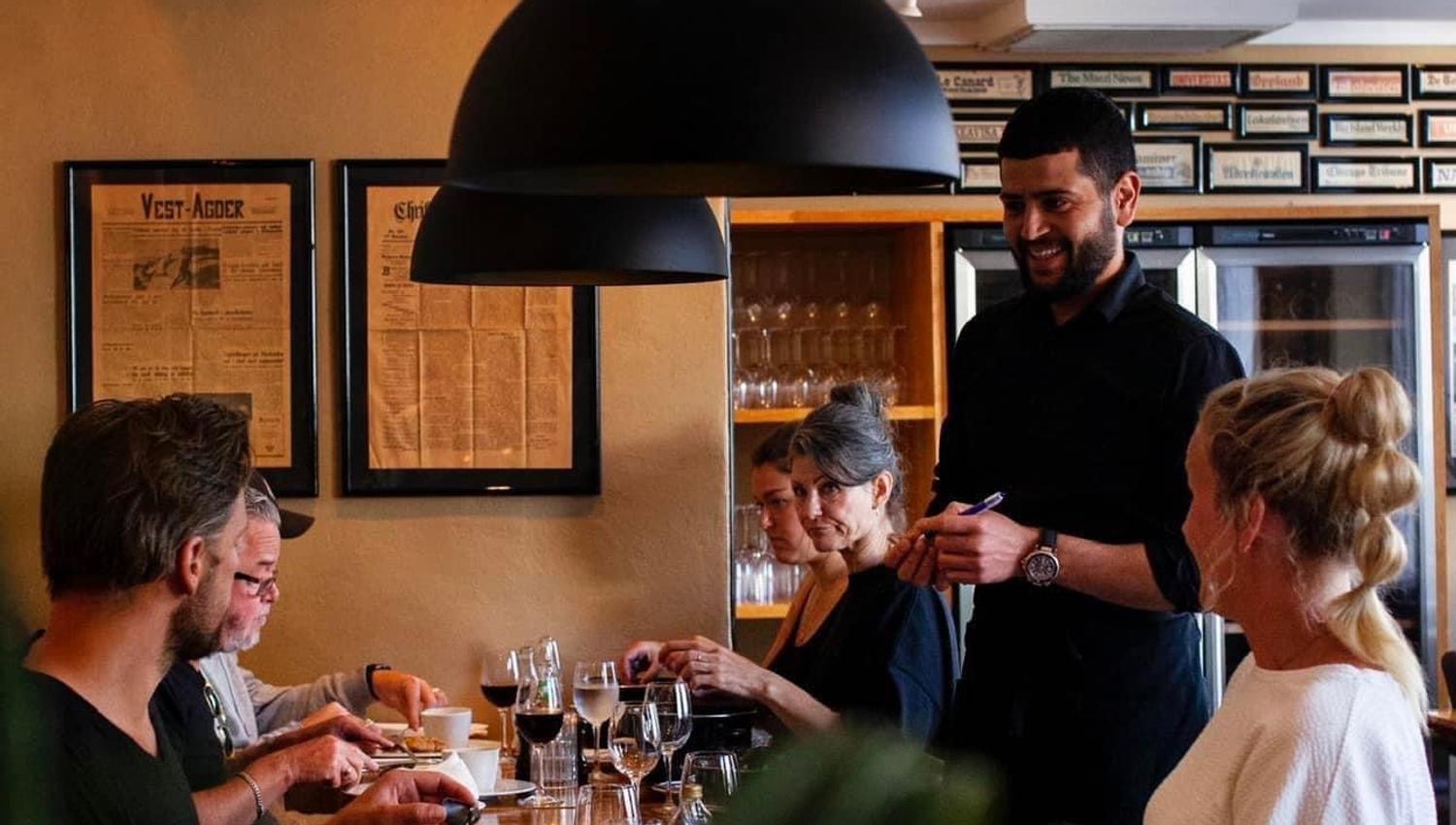 Waiter serving smiling guests.
