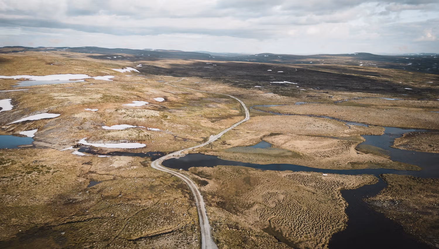 A drone photo of the Tinnhølvegen road, witha cloudy sky in the background.