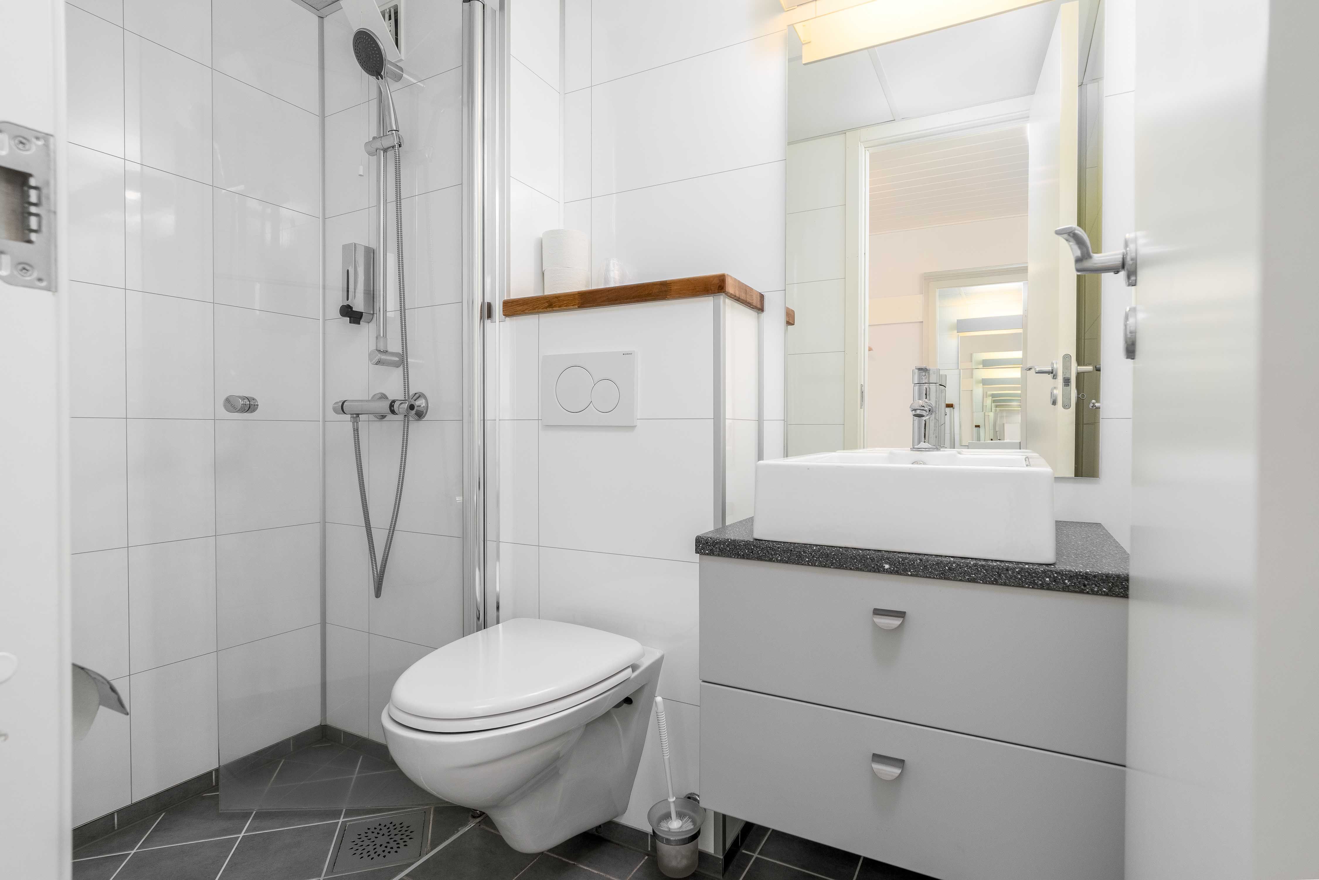 Reint og moderne bad på Husnes Sentrum Hotell med dusj og lyse fliser.
