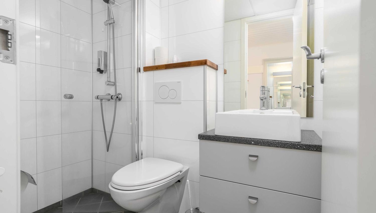 Clean and modern bathroom at Husnes Sentrum Hotel with shower and bright tiles.