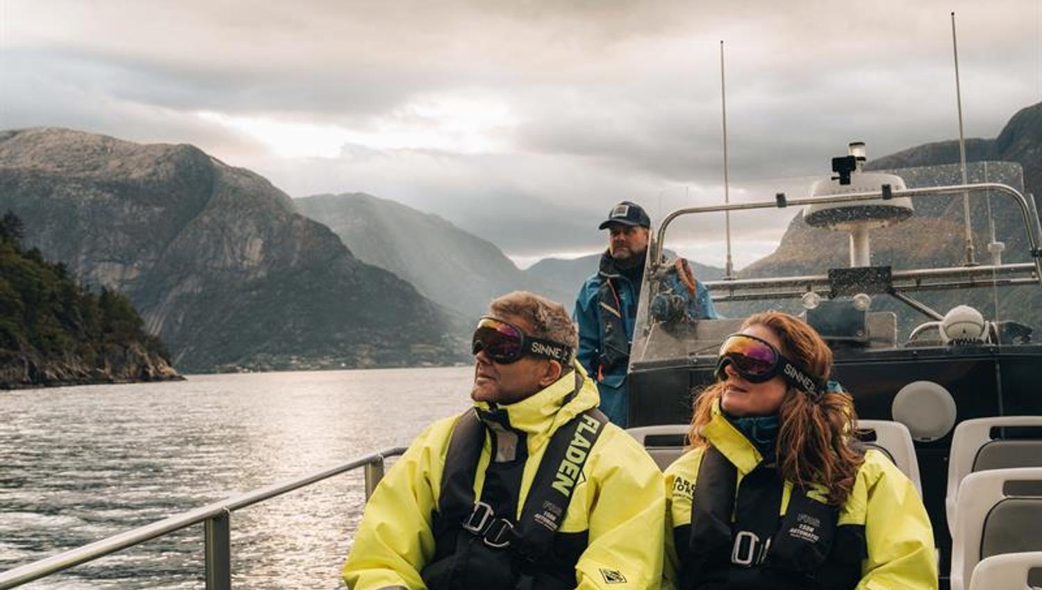 A couple and the captain onboard a rib boat, gazing towards the sky.