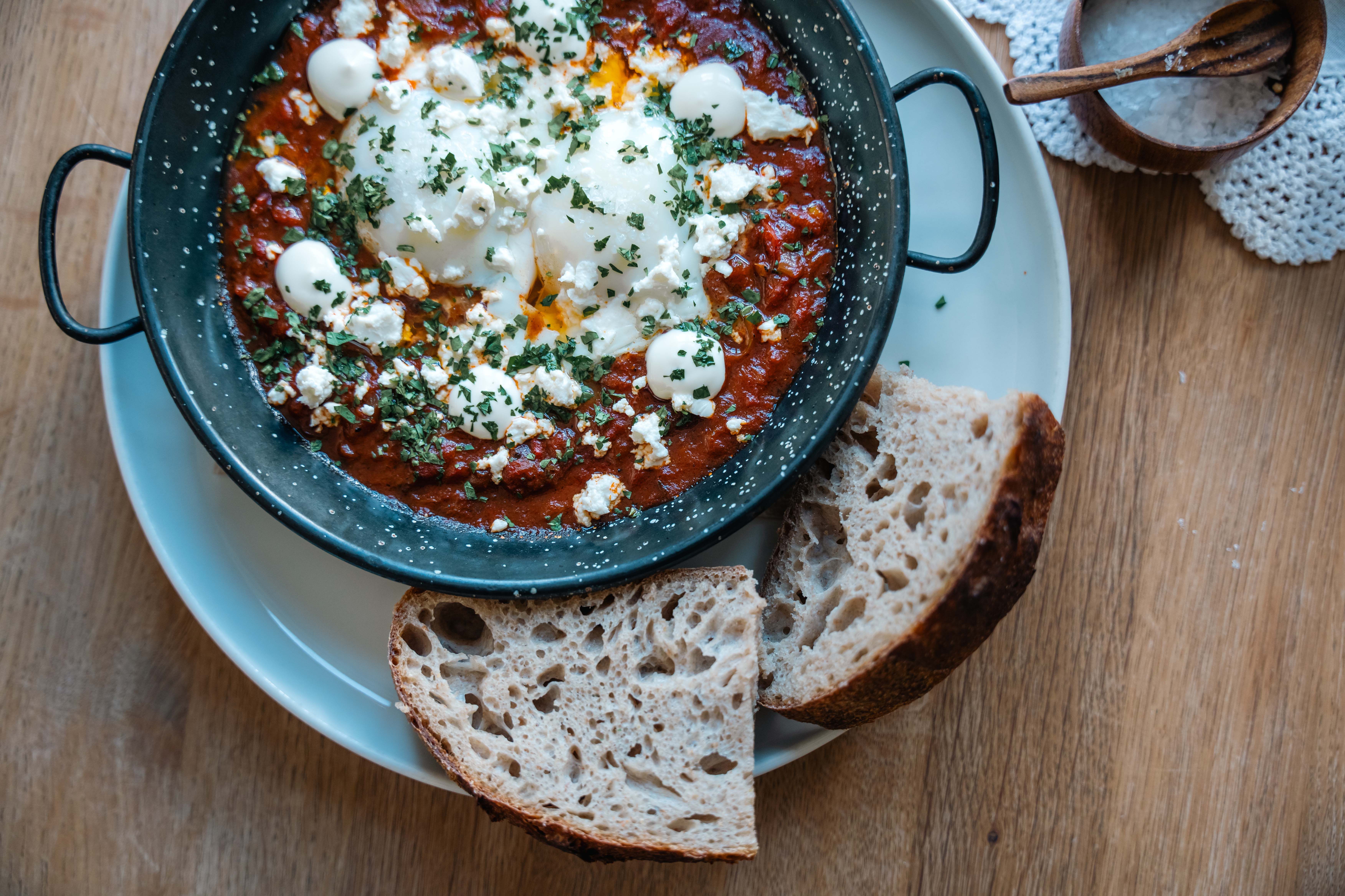A dish containing eggs, tomato sauce and cheese.