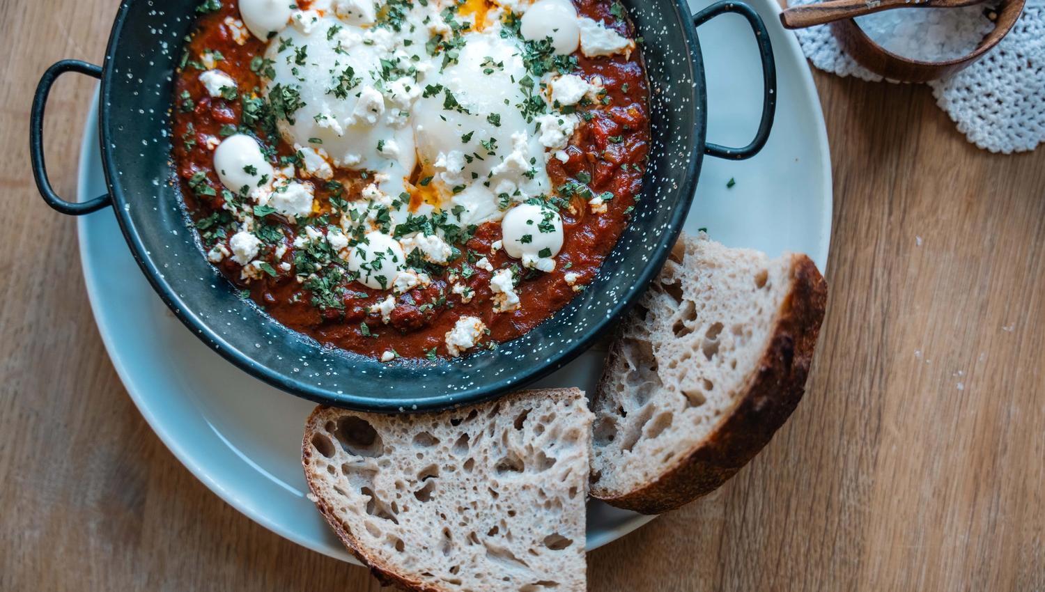 A dish containing eggs, tomato sauce and cheese.