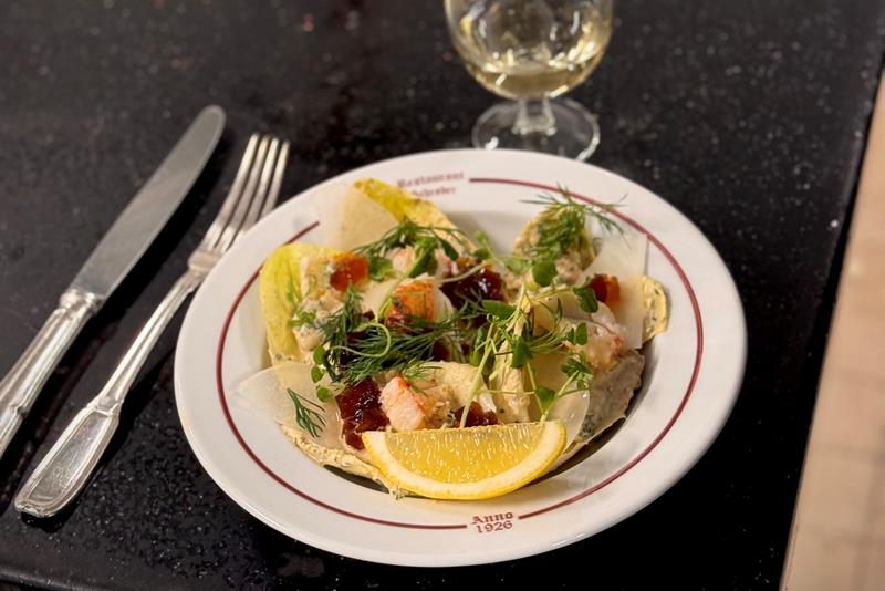 Delicate seafood dish with shellfish, herbs and lemon served with a glass of white wine.