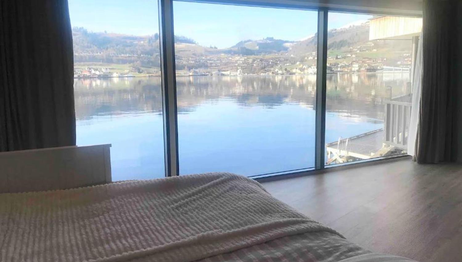 Dreamlike view of the Hardangerfjord from an elegant bedroom with large panoramic windows.