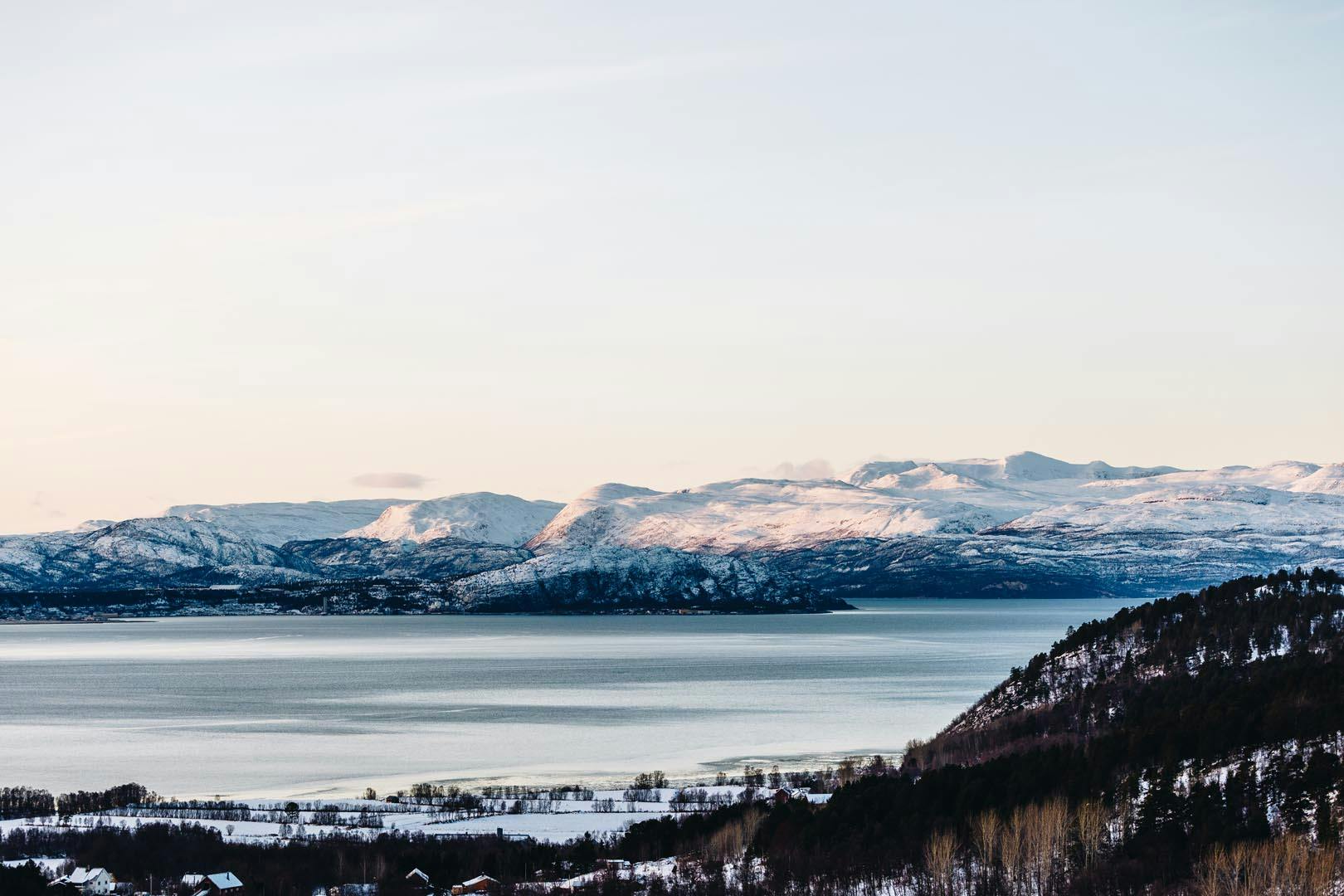 Vue panoramique des montagnes enneigées au bord d'un lac calme.