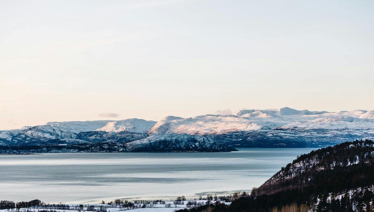 Vue panoramique des montagnes enneigées au bord d'un lac calme.