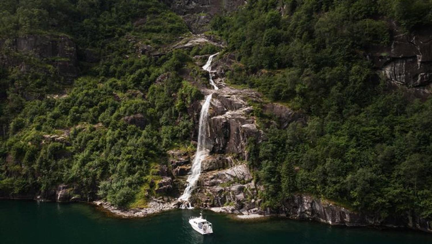 Pilagutt in front of a powerful waterfall in the Hardangerfjord – a magical place for nature experiences on the fjord.
