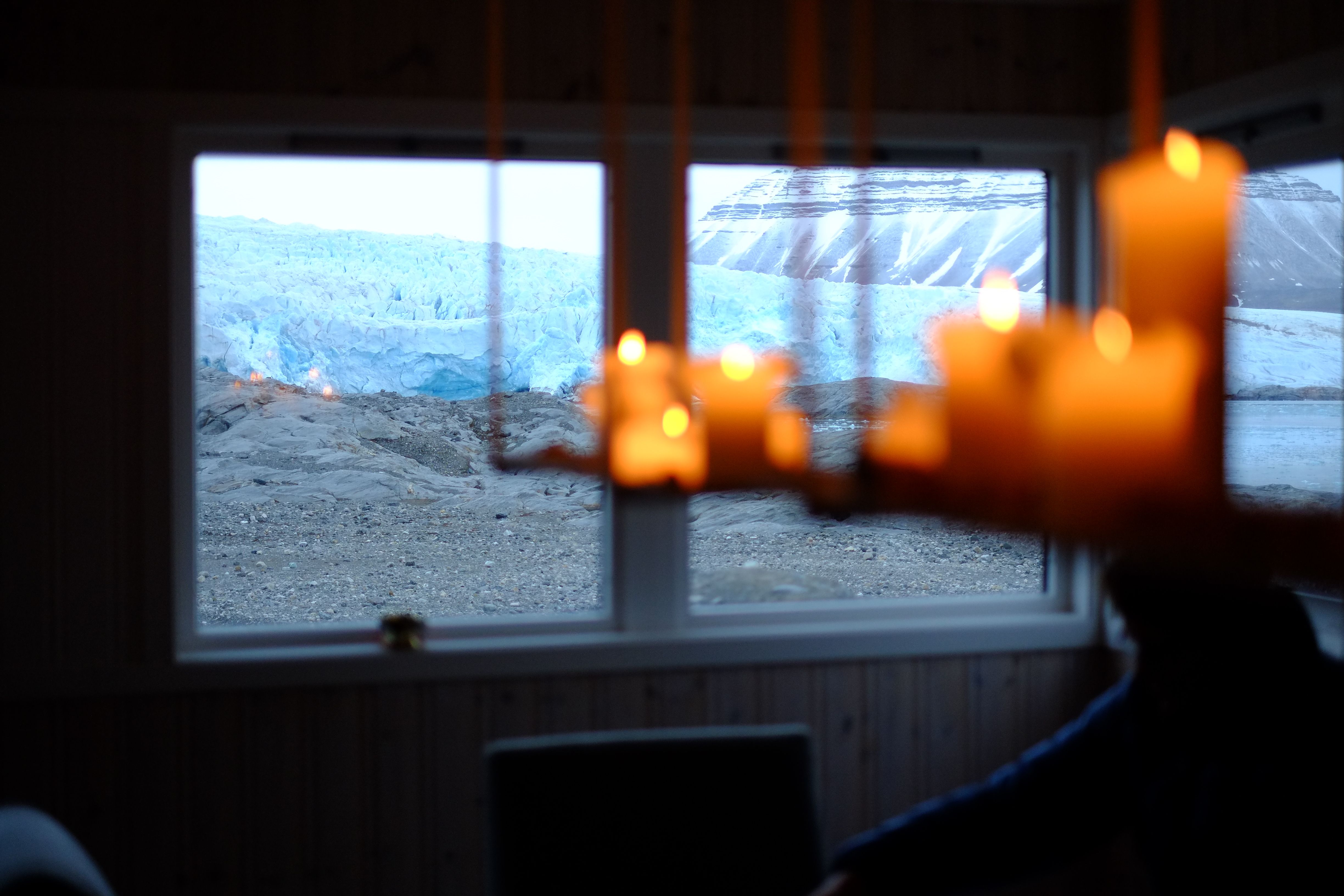 Chandelier with candles and the view of Nordenskiöld Glacier through the windows at Nordenskiöld Lodge.