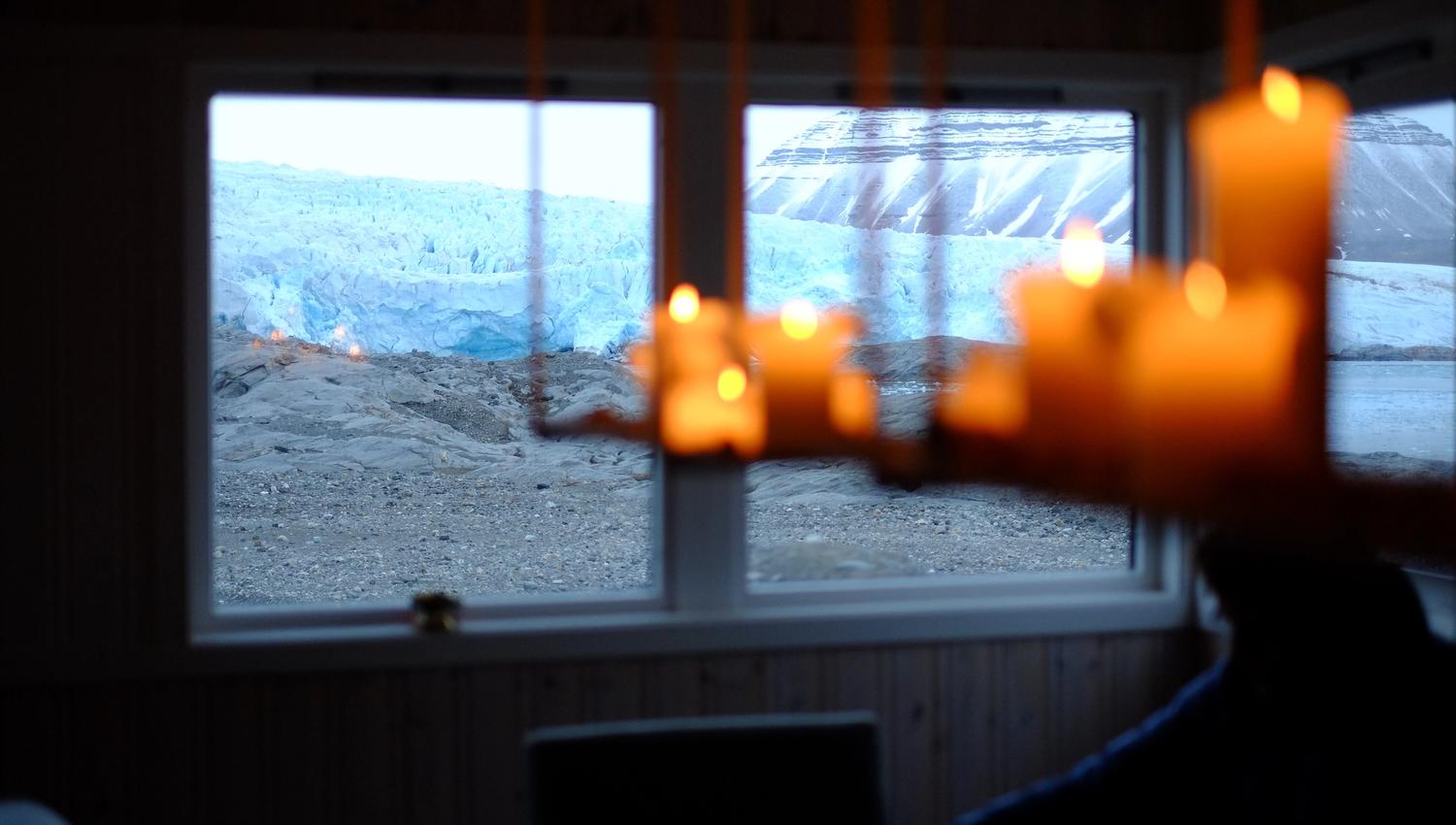 Chandelier with candles and the view of Nordenskiöld Glacier through the windows at Nordenskiöld Lodge.