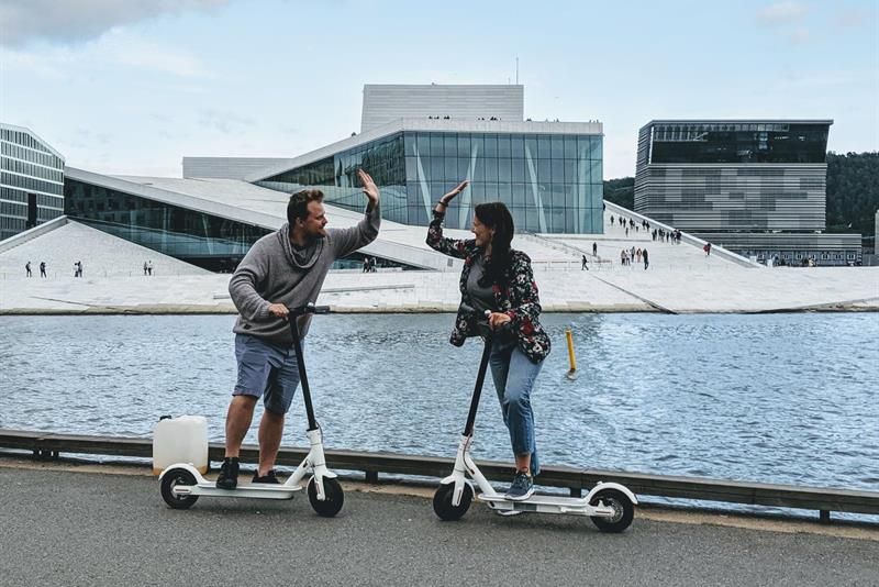 Two persons with e-scooters in front of the Opera House