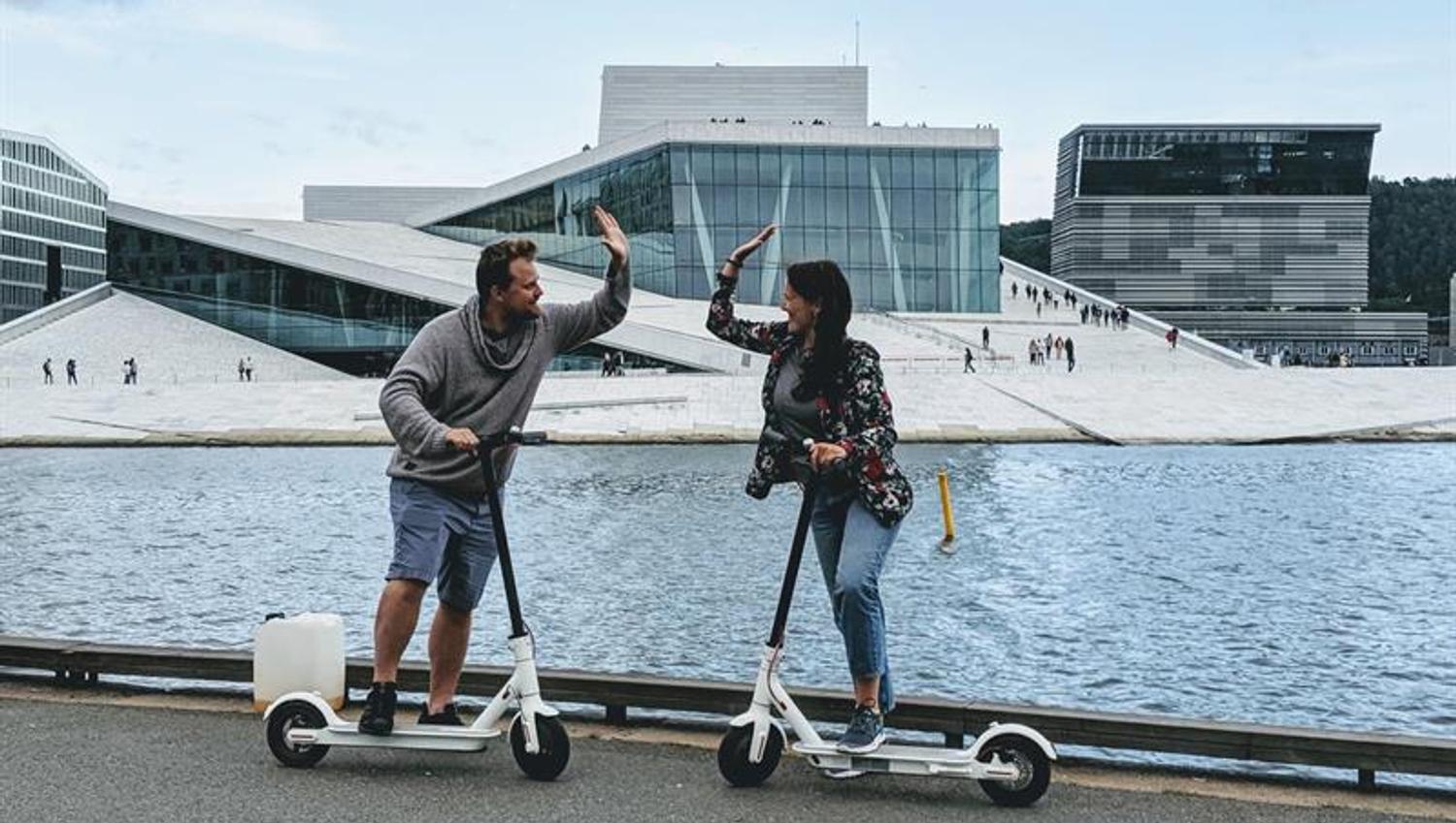 Two persons with e-scooters in front of the Opera House