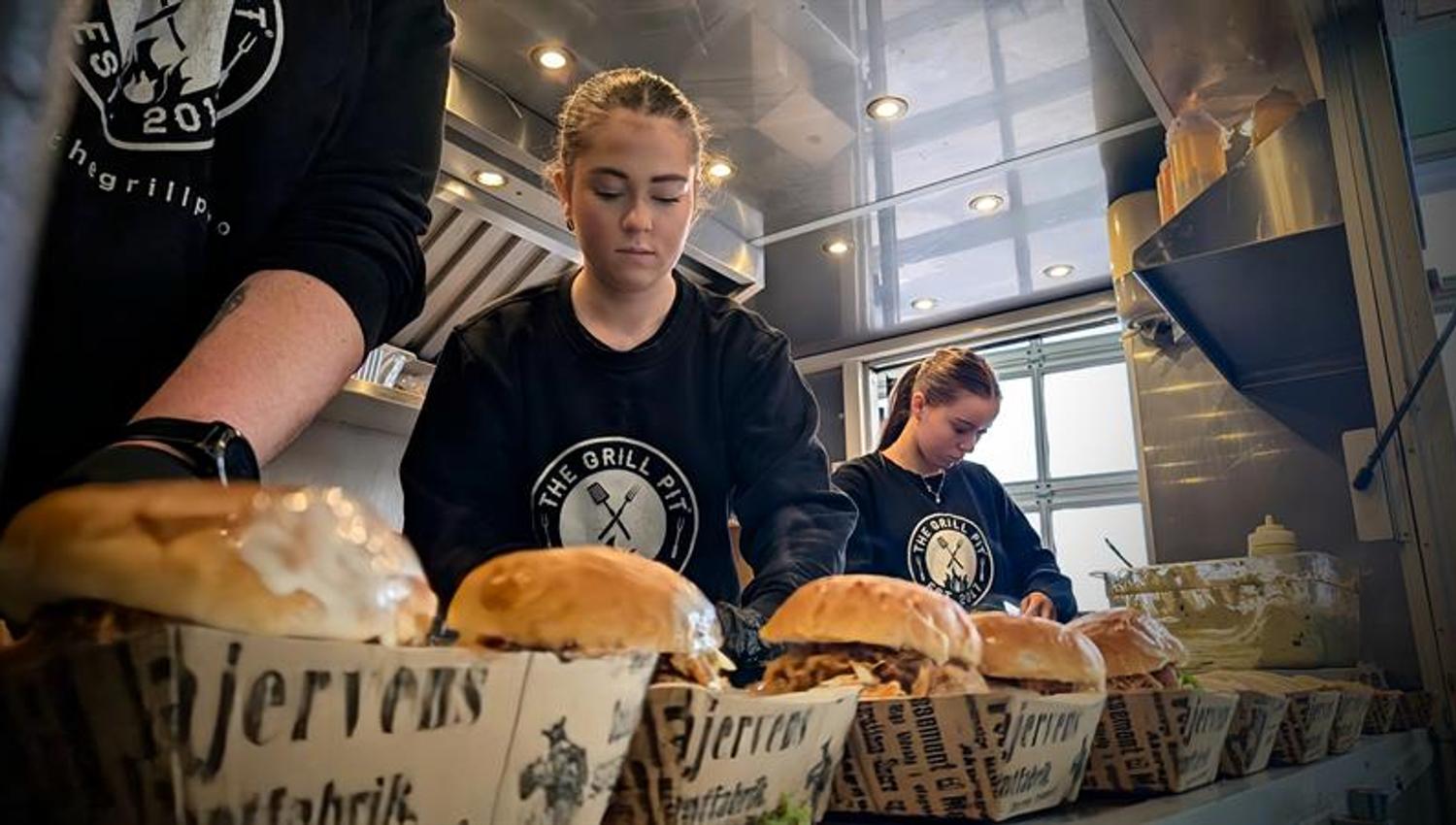 Ansatte på kjøkkenet hos The Grill Pit tilbereder burgere.