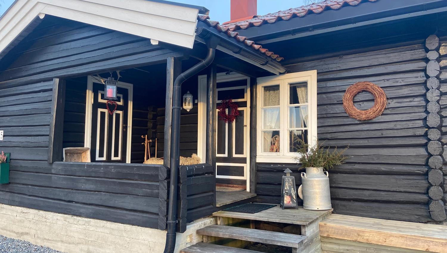 svart hytte med inngangsparti