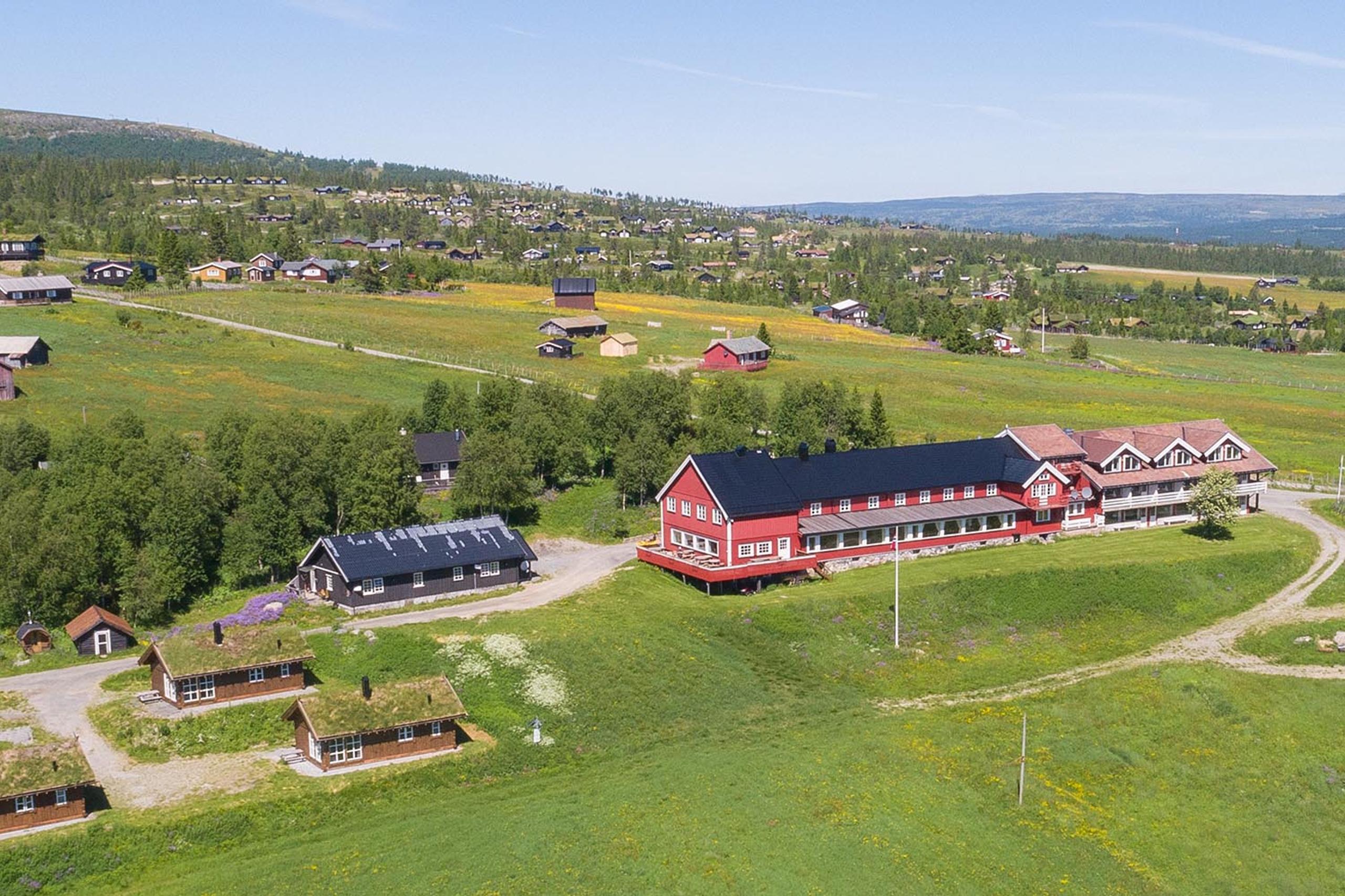 Done footage of a red wooden hotel in a green summer meadow landscape