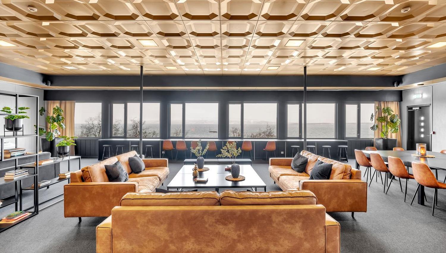 Moderne lounge med skinnsofaer, store vinduer og dekorative detaljer.