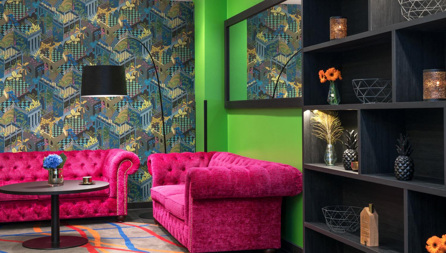 To sofaer i pink foran en eplegrønn vegg og en tapetvegg. Thon Hotel Terminus i Oslo. Foto.